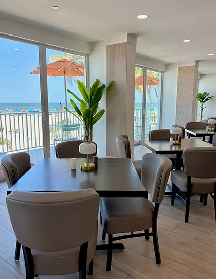 Interior of Grace’s Trattoria with elegant tables, modern chairs, and floor-to-ceiling windows overlooking the Gulf of Mexico.